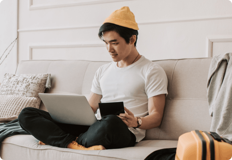 A man sitting on the couch checking insurance on his laptop.