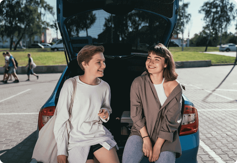 Two friends hanging out by their car