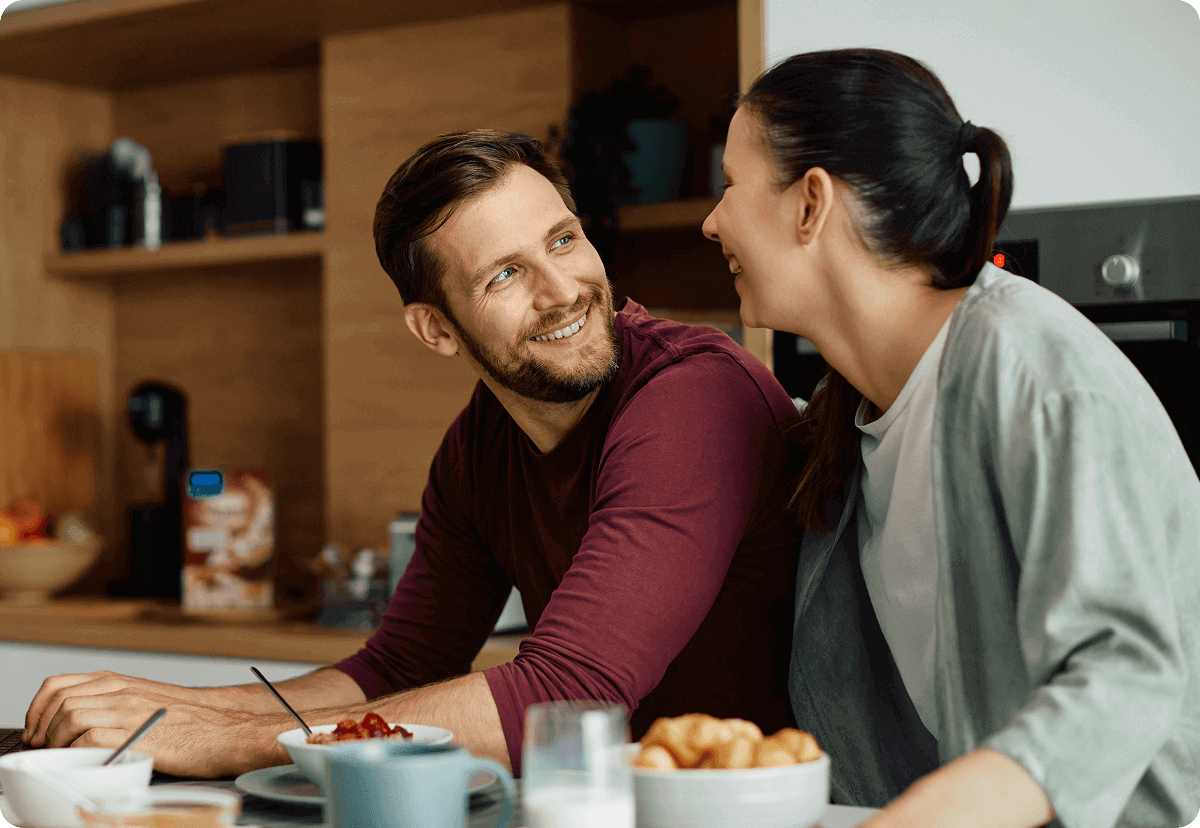 Young expat couple in their kitchen researching health insurance for an Italian visa.