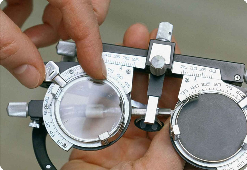 A close-up of an optometrist adjusting a trial lens frame used for eye exams, with hands delicately fine-tuning the dials.