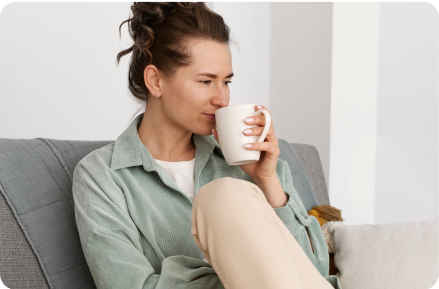 Woman drinking tea on a sofa.