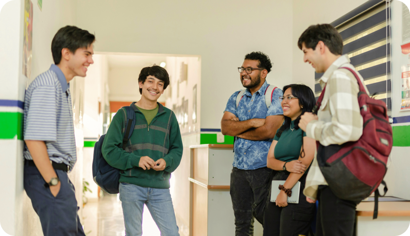 A group of student standing in a school hall, talking and smiling.