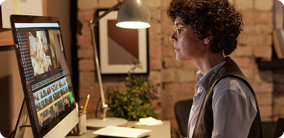 A woman working at her desk, in front of a computer screen, editing a video.