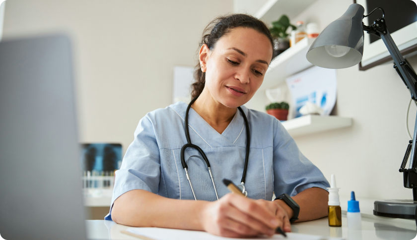 A doctor in her office writing a prescription.