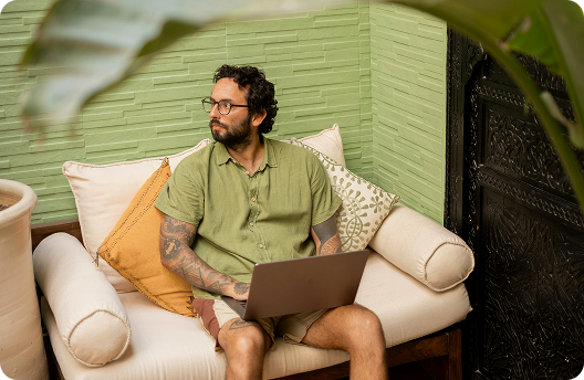 Hombre sentado en un sofá, trabajando en su computadora portátil.