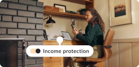 A woman working at her desk in Netherlands, adding income protection to her life insurance policy.
