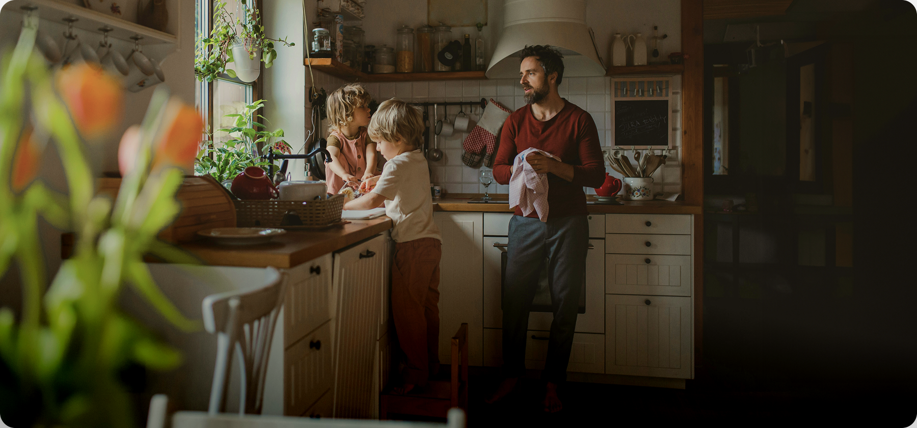 A father and two young children doing the dishes together in a warm, homely kitchen in Spain.