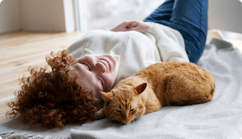 Woman laying with her ginger cat after veterinary visit
