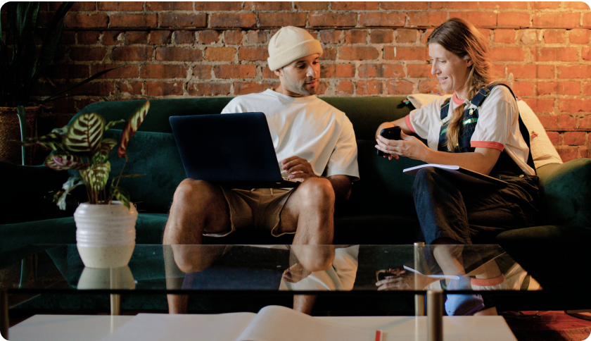 Person sitting on a couch showing her phone to a man sitting next to her. 